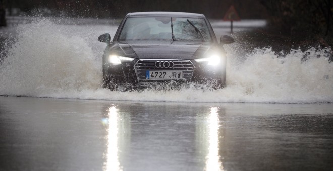 19/12/2019.- Un coche cruza la carretera LU-P-1701, en Muimenta, Lugo, inundada por el agua de los ríos Pequeño y Miño. EFE/ Eliseo Trigo