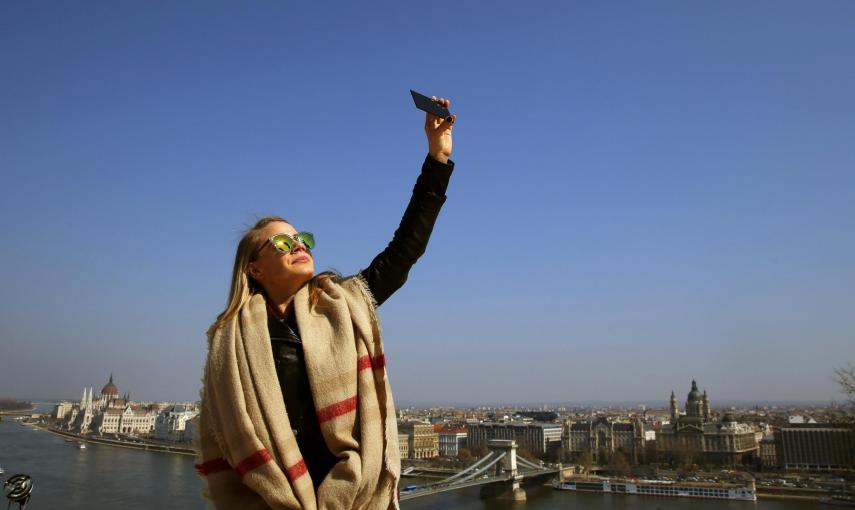 Una mujer en Budapest (Hungría) trata de ver el eclipse parcial de sol a través de un cristal oscuro. REUTERS/Laszlo Balogh