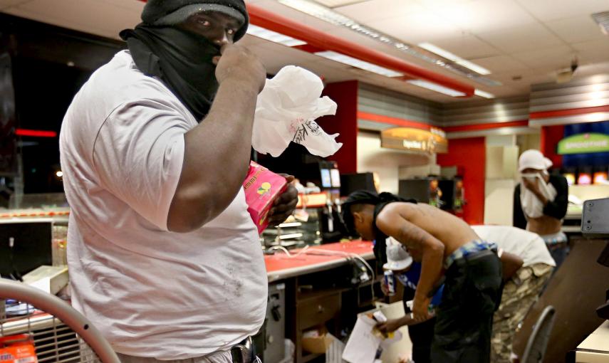 Un saqueador armado con una pistola en la cintura roba artículos de un QuikTrip después de los disturbios que estallaron al final de una vigilia por Michael Brown en Ferguson , Missouri en agosto de 2014.  El St. Louis Post-Dispatch ha recibido el premio