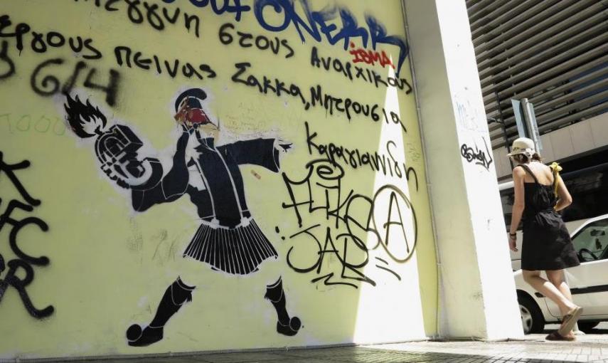 Una mujer pasea al lado de un mural en el centro de Atenas. - REUTERS