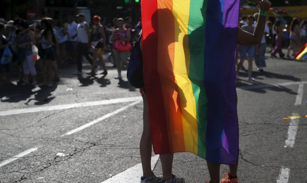 Dos manifestantes se cubren con la bandera arcoíris durante la marcha del Orgullo. REUTERS/Javier Barbancho
