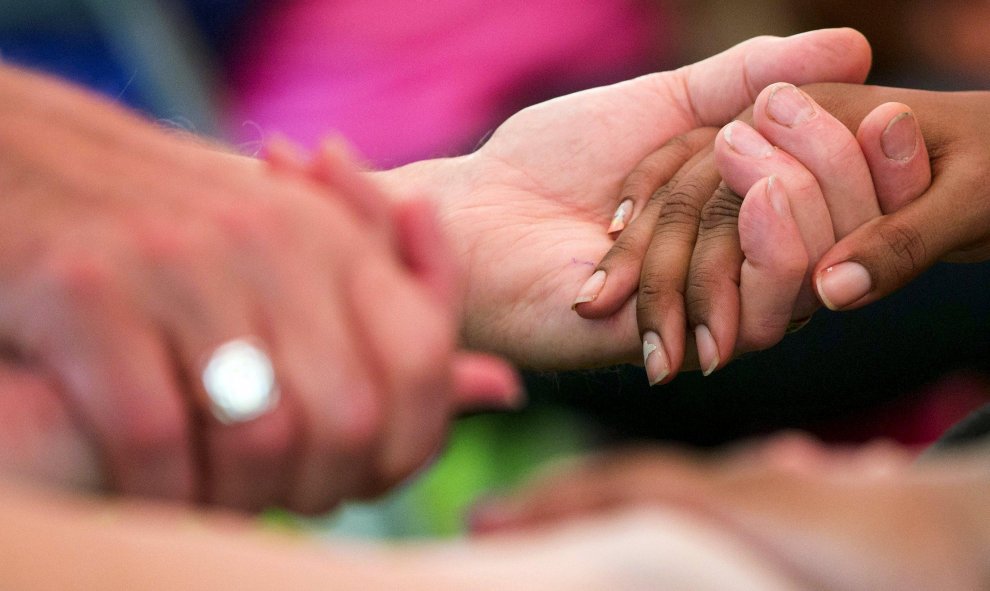 Los residentes locales y voluntarios de las iglesias cercanas se dan la mano durante un evento de la comunidad en Ferguson. REUTERS