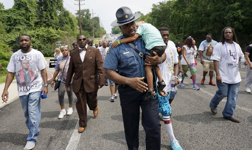 El capitán Ron Johnson de la patrulla Estatal de Missouri lleva durmiendo a un niño pequeño llamado Edwards durante una marcha de protesta en Ferguson. REUTERS