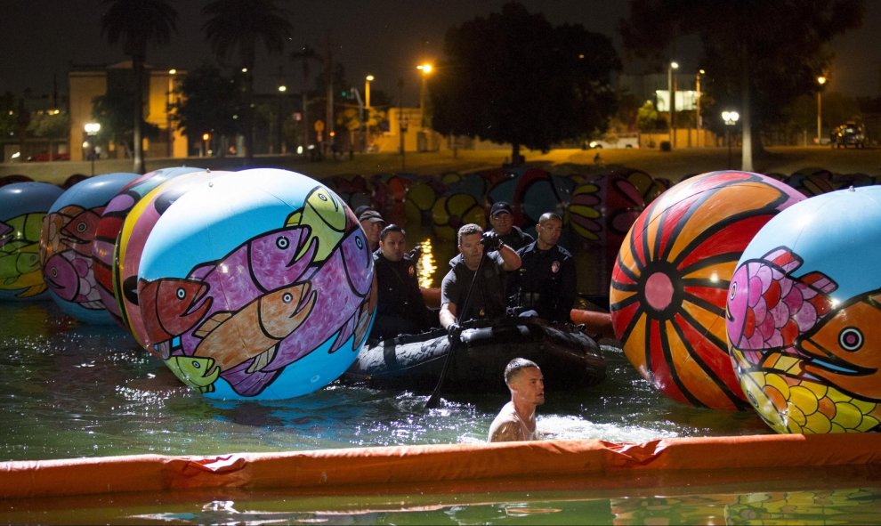 Oficiales de la policía de Los Ángeles y los miembros de la Unidad de Buceo Submarino acercan a una persona a través de la exposición "Esferas de MacArthur Park" en Los Ángeles, California 24 de agosto de 2015. REUTERS / Mario Anzuoni