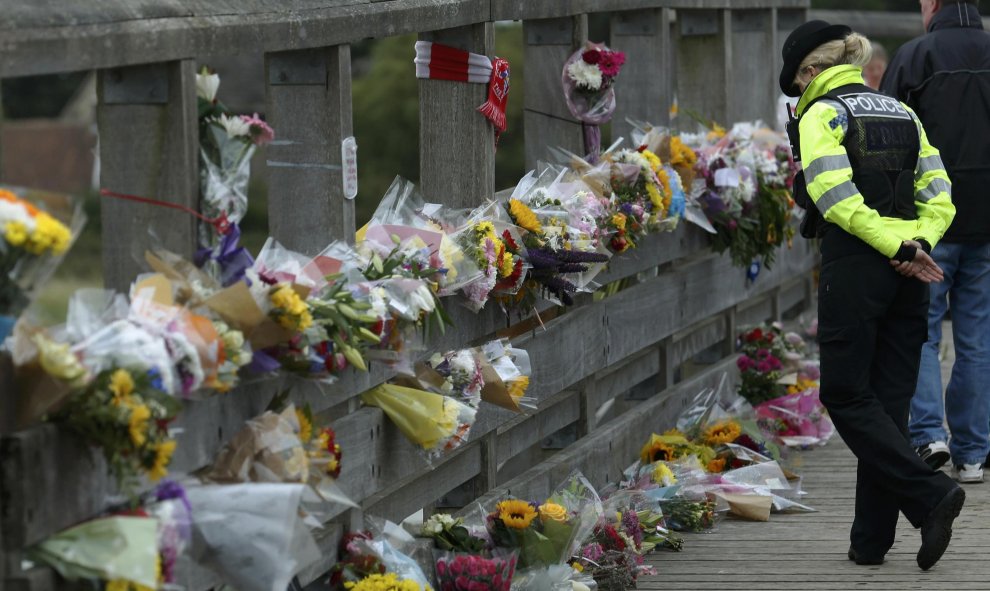 Una oficial de la policía observa las ofrendas que dejan cerca de donde se estrelló un jet de combate Hawker Hunter en una exhibición de acrobacia en la carretera A27 en Shoreham cerca de Brighton, Reino Unido 25 de agosto de 2015. Según fuentes policiale