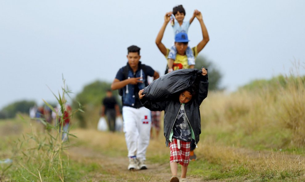 Refugiados sirios, muchos de ellos niños, caminan después de cruzar la frontera húngaro-serbio en Hungría, cerca Röszke, y sortear la alambrada de cuchillas recién instalada.-REUTERS / Laszlo Balogh