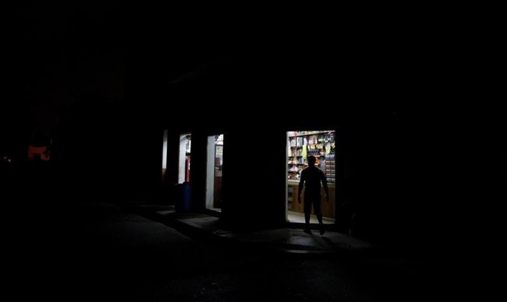 Un hombre ingresa a un almacén hoy, viernes 28 de agosto de 2015, durante un apagón debido a que el 85% del país se encuentra sin energía eléctrica tras el paso de la tormenta tropical Erika, en la zona colonial en Santo Domingo (República Dominicana). La