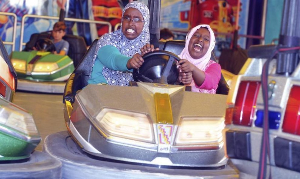 Dos niñas refugiadas se divierten en los coches de choque, en Augsburgo, Alemania. EFE/Stefan Puchner