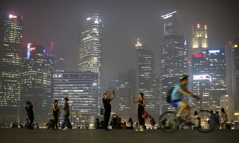 La gente toma fotos con el distrito central de negocios de Singapur de fondo. REUTERS