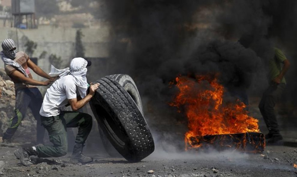 Palestinos lanzan queman neumáticos durante una protesta contra los asentamientos judíos en Wadomem cerca de Nablus (Palestina). Nueve palestinos han resultado heridos durante los enfrentamientos con los soldados durante la manifestación. EFE/Alaa Badarne