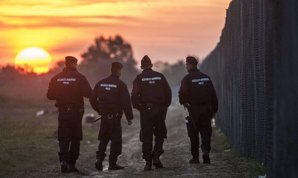 Policías húngaros patrullan al amanecer a lo largo de la valla fronteriza en Roszke (Hungría). EFE/SANDOR UJVARI