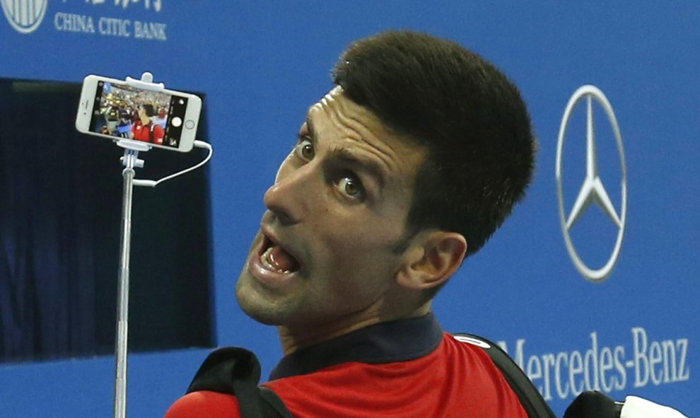 Novak Djokovic de Serbia haciéndose un selfie con el teléfono móvil de un fan después de ganar contra Simone Bolelli de Italia en el torneo Open de China en Beijing, 06 de octubre de 2015. REUTERS / Kim Kyung - Hoon