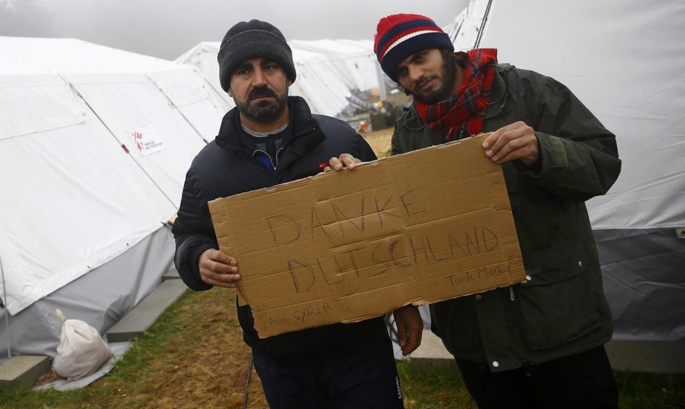 Dos refugiados  del campamento temporal de Schwarzenborn (Alemania) sostienen una cartón en el que han escrito, en alemán, "Gracias Alemania". REUTERS/Kai Pfaffenbach