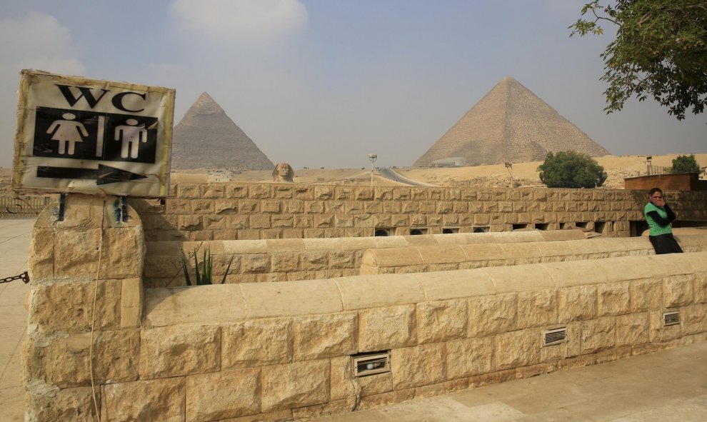 Una mujer espera en frente de un baño cerca de las  pirámides de Giza, en las afueras de El Cairo (Egipto). REUTERS / Amr Abdallah Dalsh