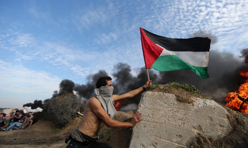 Un manifestante coloca una bandera palestina durante los enfrentamientos con las tropas israelíes cerca de la frontera entre Israel y el centro de la Franja de Gaza. REUTERS/Ibraheem Abu Mustafa