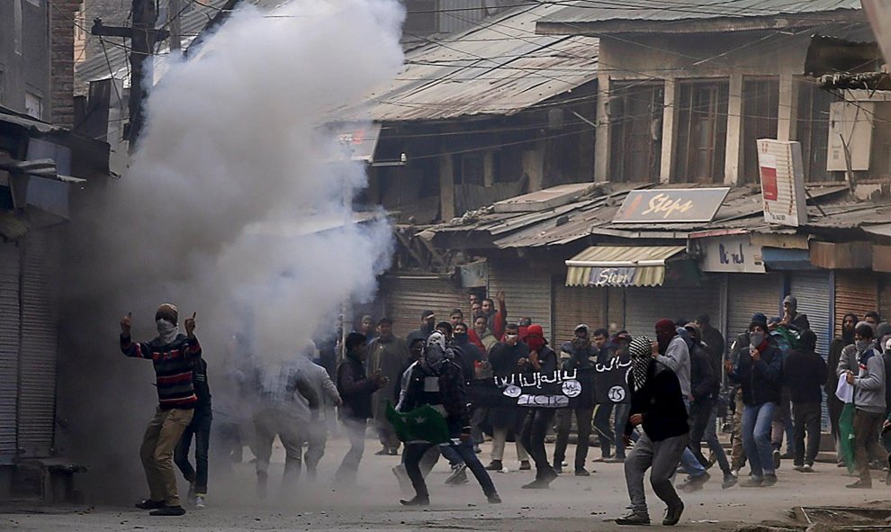Manifestantes de Cachemira sostienen una bandera similar a la bandera utilizada por el Estado Islámico en medio del humo del gas lacrimógeno lanzado por la policía de la India durante una protesta en Srinagar. Los manifestantes exigían la libertad de la d