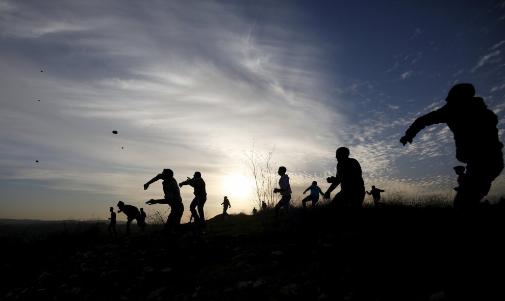 Protestantes palestinos lanzan piedras hacia las tropas israelíes en la ciudad de Ramallah. REUTERS/Mohamad Torokman