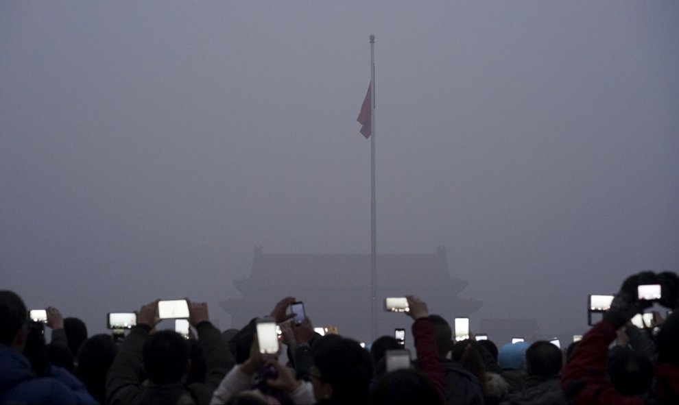 Unos turistas fotografían la ceremonia de la bandera en la plaza de Tiananmen mientras la contaminación sigue sin dar tregua. Pekín, China. REUTERS/Stringer