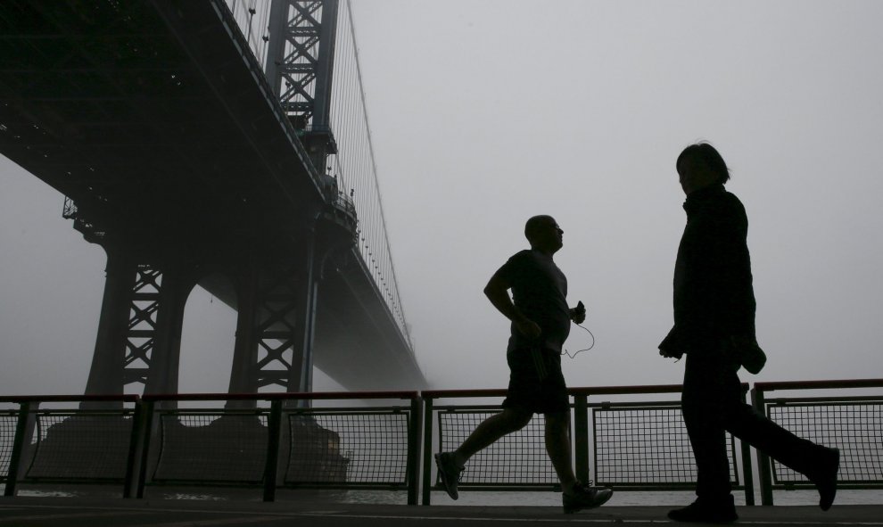 Siluetas de personas haciendo ejercicio en el Puente de Manhattan cubierto por la niebla en Nueva York. REUTERS/Shannon Stapleton