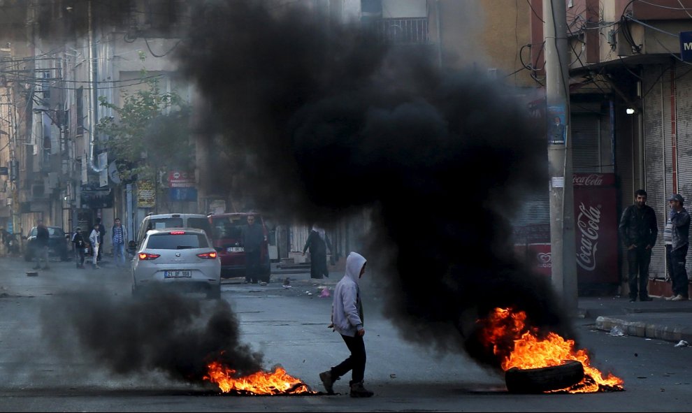 Un niño camina entre neumáticos en llamas durante una protesta contra el toque de queda en el distrito Sur, en la ciudad suroriental de Diyarbakir, Turquía. REUTERS/Sertac Kayar