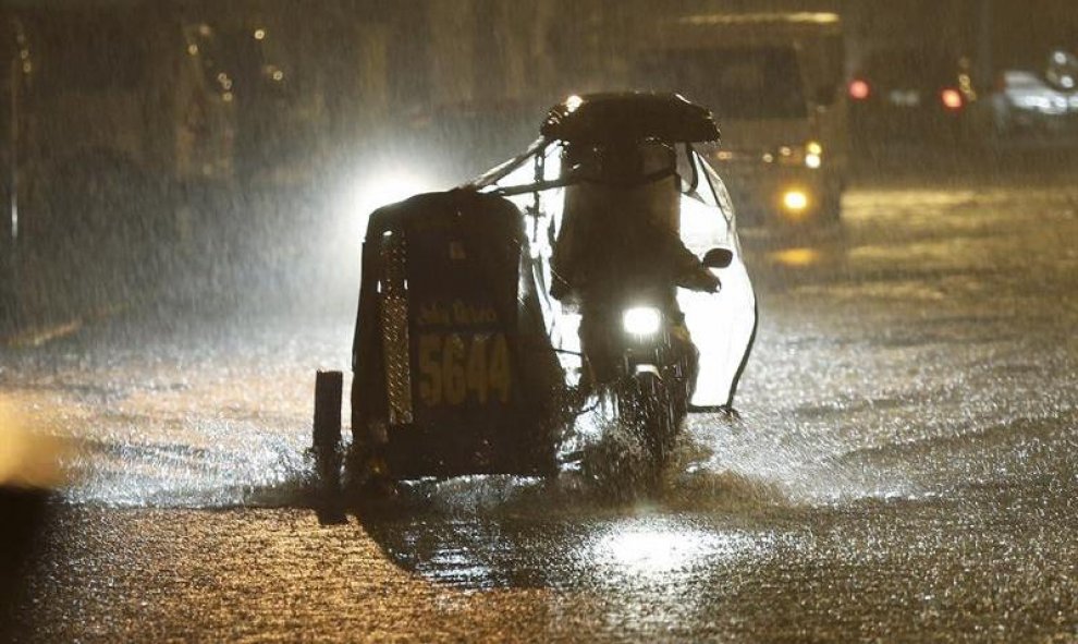Un vehículo circula bajo una intensa lluvia por una calle inundada en Manila (Filipinas). Al menos una persona ha muerto y 733.000 más tuvieron que ser evacuadas en Filipinas debido al tifón Melor, que desde ayer azota la región central del país con inten