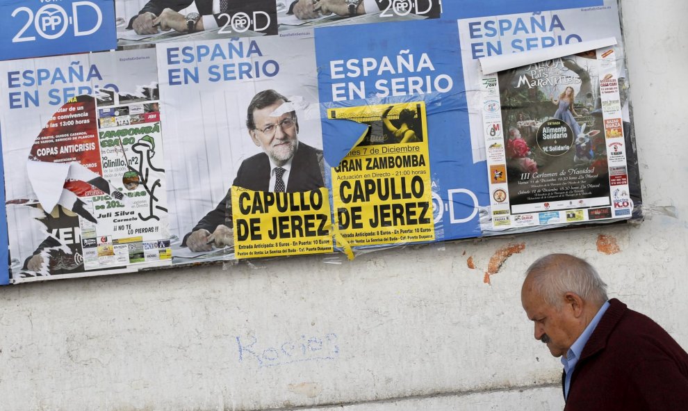 Un hombre pasea junto a varios carteles electorales de Mariano Rajoy en Sanlucar de Barrameda (Cádiz). REUTERS/Marcelo del Pozo
