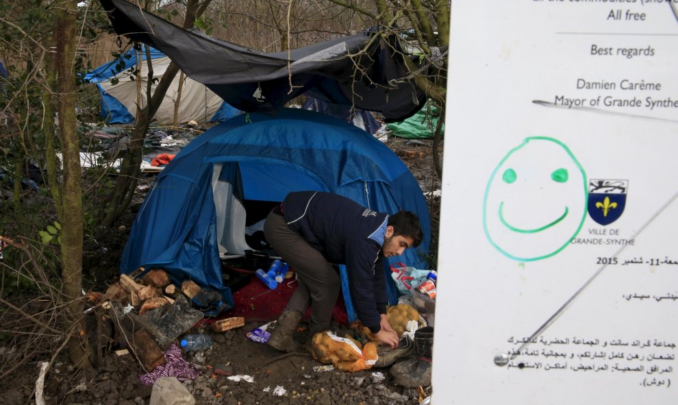 Un inmigrante limpia los alrededores embarrados de su tienda en el campamento provisional para refugiados de procedentes de Irak, Kurdistán, Irán y Siria, cerca de Dunkerque (Francia). REUTERS / Pascal Rossignol