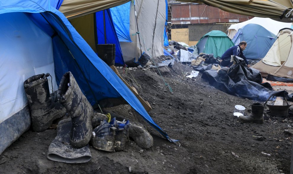 Botas y zapatos embarrados jnto a las tiendas del campamento provisional para refugiados de procedentes de Irak, Kurdistán, Irán y Siria, cerca de Dunkerque (Francia). REUTERS / Pascal Rossignol