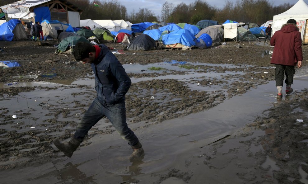Un inmigrante camina por el suelo enfangado del  campamento provisional para refugiados de procedentes de Irak, Kurdistán, Irán y Siria, cerca de Dunkerque (Francia). REUTERS / Pascal Rossignol