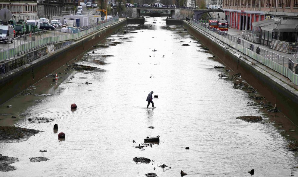 Un trabajador entra en el agua durante el drenaje del Canal Saint-Martin en París. REUTERS/Charles Platiau