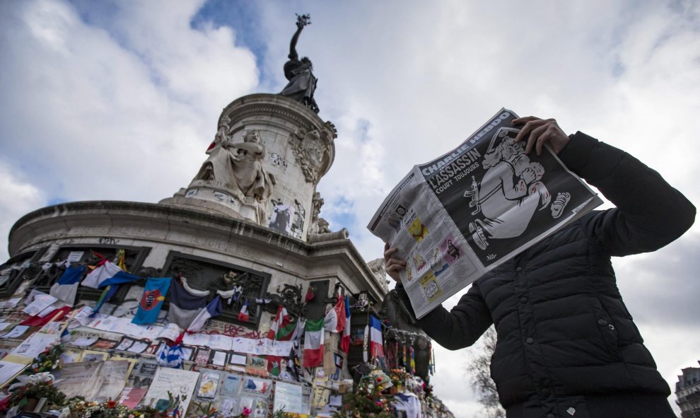 Un hombre ojea el número especial publicado por el semanario satírico 'Charlie Hebdo' con motivo del primer aniversario del atentado yihadista contra su redacción, en la Plaza de la República de París. EFE/Ian Langsdon