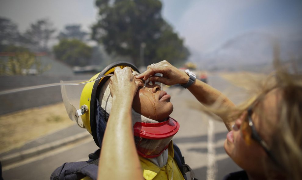 Una doctora echa solución salina en los ojos de un bombero en una calle de Ciudad del Cabo, Sudáfrica. EFE/NIC BOTHMA