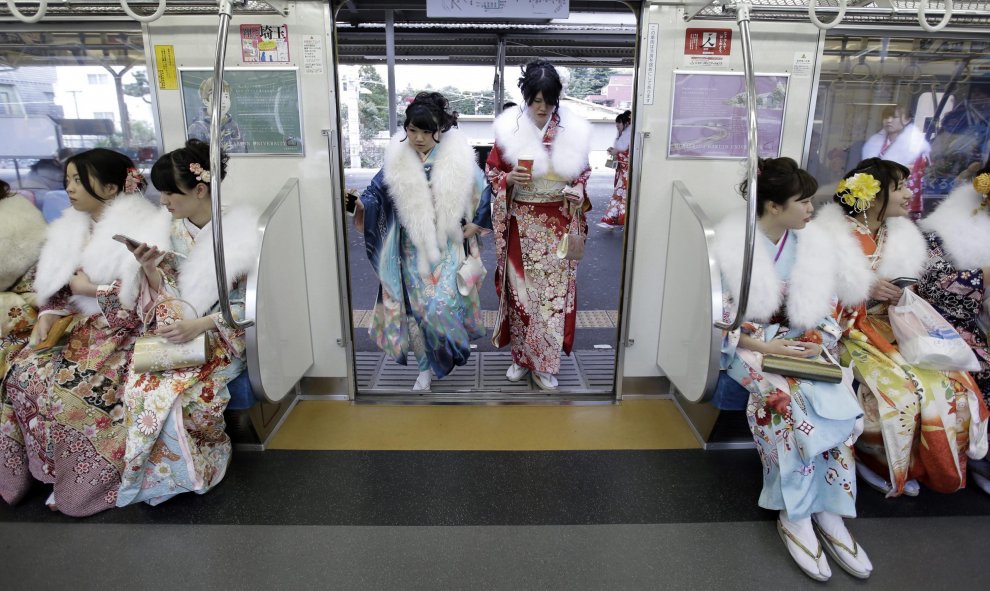 Jóvenes japonesas ataviadas con coloridos kimonos suben a un vagón de un tren tras asistir a su ceremonia de mayoría de edad en el parque de atracciones Toshimaen en Tokio. EFE/Kiyoshi Ota