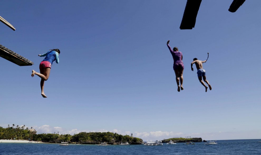 Unos turistas saltan al agua desde una de los islotes de la Isla de Boracay (Islas Filipinas) a 20 metros de altura. REUTERS/Charlie Saceda