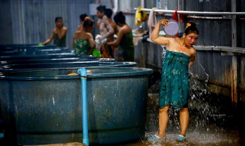 Trabajadoras migrantes se asean en unos baños comunitarios en el asentamiento de Samut Prakan, a las afueras de Bangkok (Tailandia). Cientos de obreros de la construcción habitan un singular asentamiento erigido a las afueras de Bangkok con contenedores d