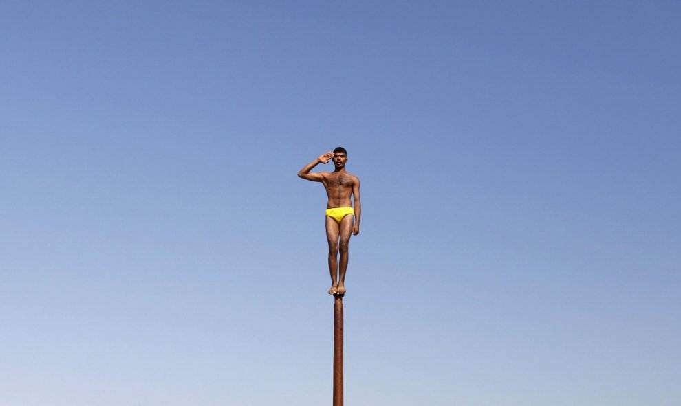 Un soldado del ejército indio realiza 'Malkhamb', gimnasia tradicional india, durante una campaña para atraer a los jóvenes de unirse a las fuerzas armadas en la víspera del Día de la República de la India en Gandhinagar. REUTERS/Amit Dave