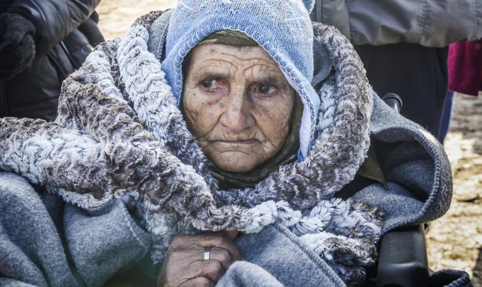 Una anciana en silla de ruedas llega junto con otros emigrantes y refugiados a la aldea de Miratovac después de cruzar a Serbia por la frontera con Macedonia, el 28 de enero de 2016./AFP/ARMEND NIMANI