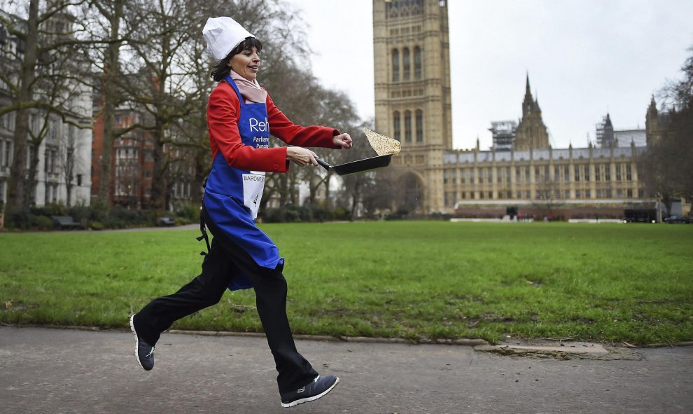 Una parlamentaria corre mientras da la vuelta a una tortita por los jardines de Victoria junto a las Casas del Parlamento en Londres, durante la tradicional carrera de tortitas para recaudar dinero para obras de caridad. EFE/Andy Rain