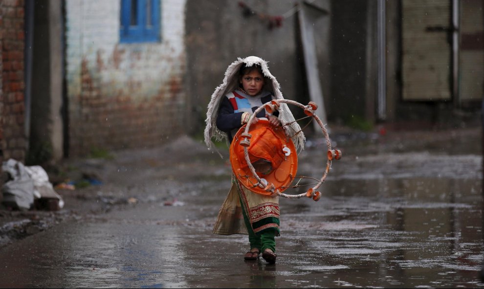 Una chica lleva un tacatá por un callejón mientras llueve en Srinagar, 17 de marzo de 2016. REUTERS / Danish Ismail