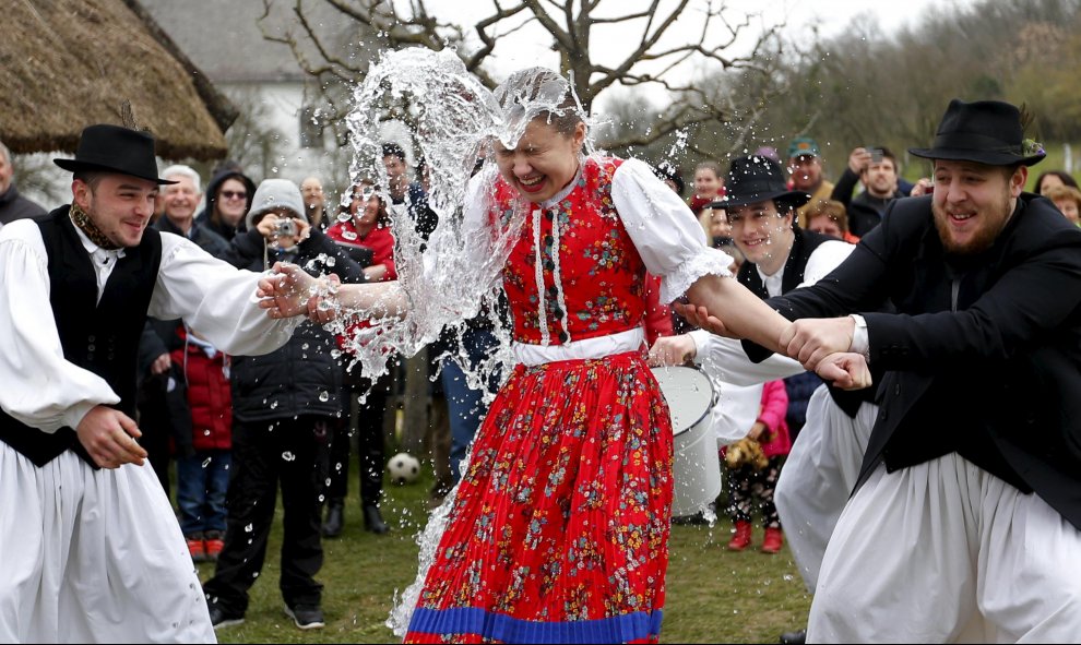 Un grupo de hombres lanzan a una mujer un cubo de agua como parte de la tradición de este 'Easter Break' en Szenna, Hungría. REUTERS/Laszlo Balogh