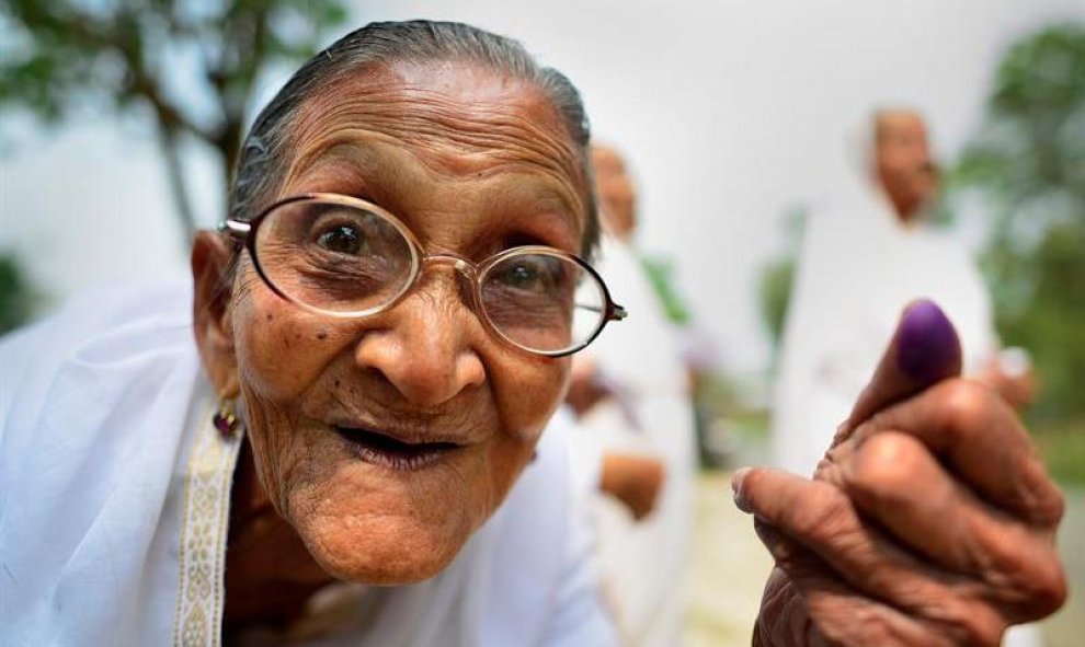 Una anciana india muestra su dedo marcado con tinta tras votar en la primera fase de las elecciones a la Asamblea de Assam, en el distrito de Jorhat, dentro del estado indio de Assam. EFE/Str