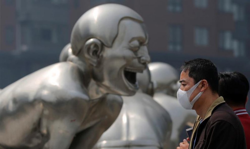 Un hombre porta una máscara junto a una estatua en Pekín, China, país que en 2015 recibió más de 15.000 quejas por los altos niveles de polución. EFE/Wu Hong
