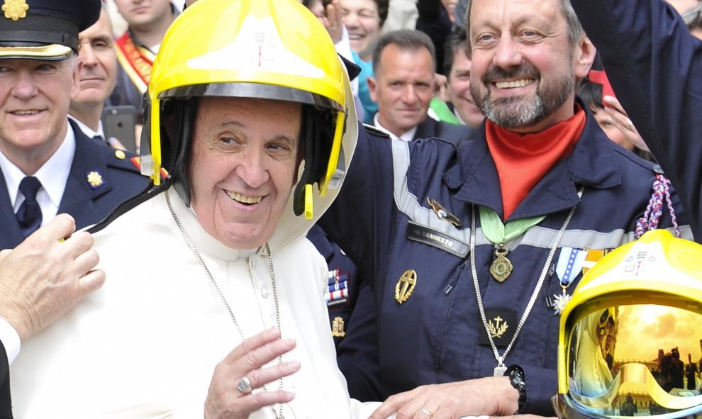 El Papa Francisco se pone el casco de los bomberos de París al final de su audiencia en el Vaticano. REUTERS/Osservatore Romano Handout via Reuters