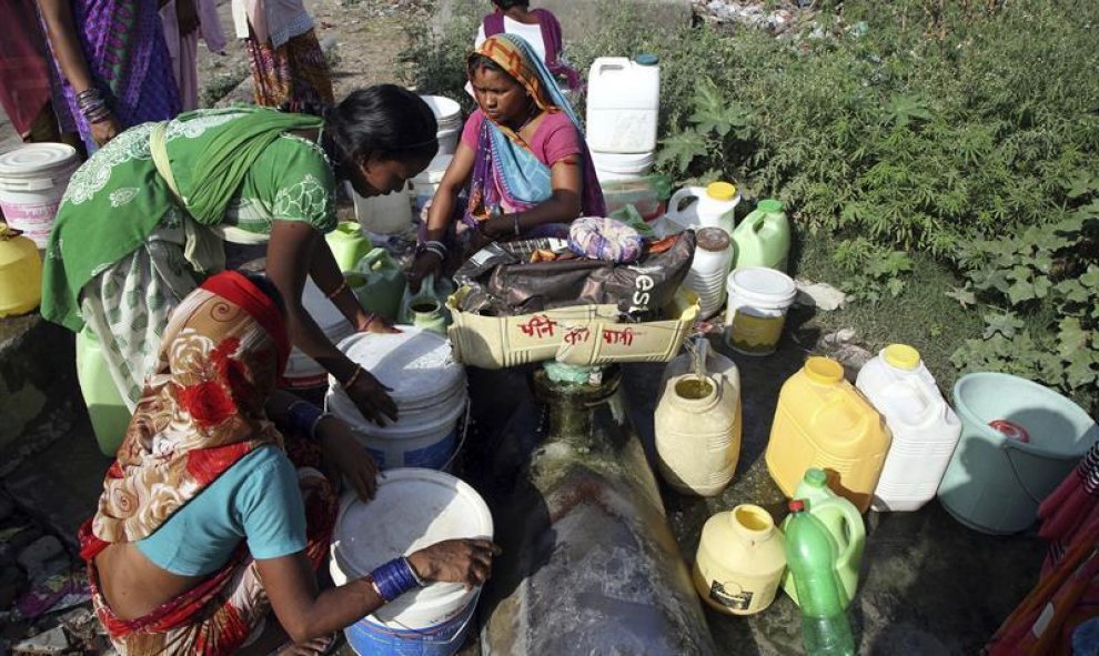 Un grupo de mujeres espera para extraer agua potable de una fuente pública  ante la escasez de suministro de agua en los hogares de los barrios más pobres de Jammu (India) la mayoría de sus vecinos dependen de las fugas de agua de las tuberías durante el