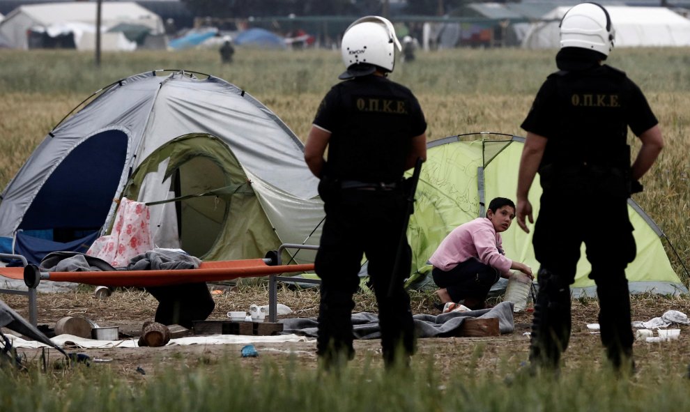 Un chico recoge sus pertenecias en presencia de dos policías durante el desalojo del campamento de Idomeni, en la frontera entre Grecia y Macedonia. REUTERS/Yannis Kolesidis