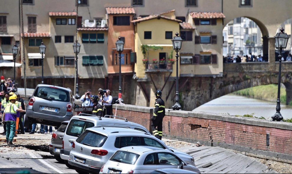 Los servicios de emergencia trabajan en la retirada de los vehículos engullidos por un socavón cerca del famoso Puente Viejo a orillas del río Arno, en el centro de la ciudad italiana de Florencia. EFE/Maurizio Degl' Innocenti