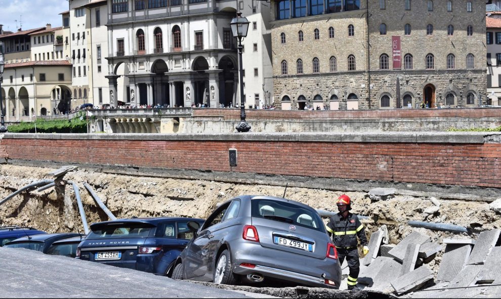 Los servicios de emergencia trabajan en la retirada de los vehículos engullidos por un socavón cerca del famoso Puente Viejo a orillas del río Arno, en el centro de la ciudad italiana de Florencia. EFE/Maurizio Degl' Innocenti