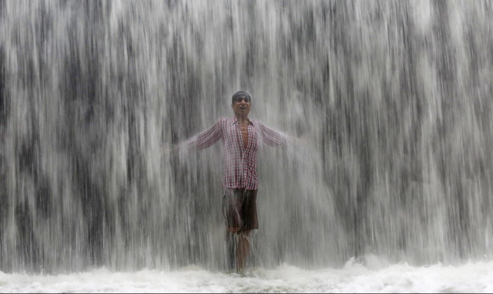 Un niño bajo el agua emanada de una presa  a lo largo del lago Powai tras fuertes lluvias en Mumbai , India.- REUTERS / Shailesh Andrad