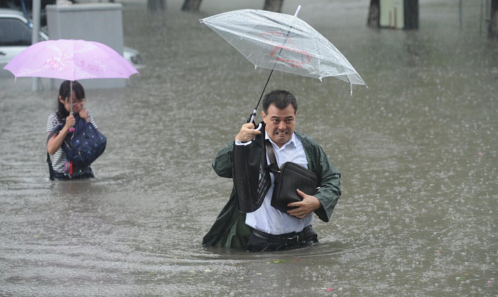 Un hombre lleva su paragüas mientras atravisa la calle entre las aguas a causa de las inundaciones en Taiyuan, en la provincia de Shanxi Province, China. China Daily/REUTERS