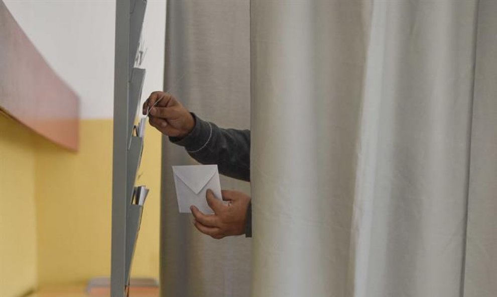 Un hombre elige la papeleta en un colegio electoral de Bilbao para depositar su voto epara las elecciones autonómicas vascas. EFE/Miguel Toña